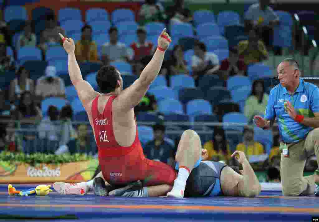 Sabah Shariati of Azerbaijan (left) celebrates after defeating Eduard Popp of Germany for the bronze medal in men's 130-kilogram Greco-Roman wrestling.