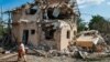 A local resident carries belongings from the ruins of her house, which was destroyed in a Russian missile strike in the Kyiv region on August 27.