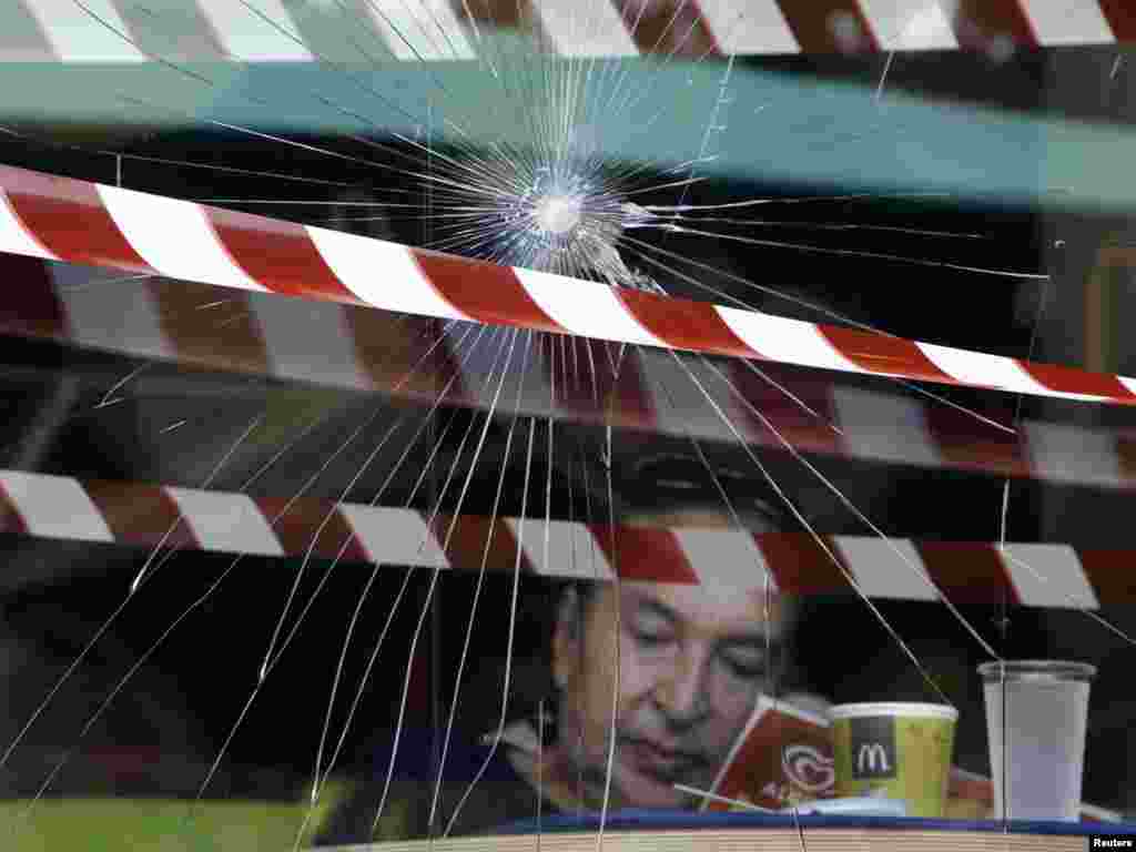 A woman sits behind a smashed window in a McDonald's fast-food restaurant after riots in Athens on June 16.Photo by John Kolesidis for Reuters