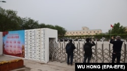 Külföldi újságírók állnak a kínai Turpanban, Hszincsiang tartományban 2021. április 22-én egy olyan épületnél, amelyet 2020 elején egy ausztrál think tank a kínai kormány átképzési létesítményeként azonosított
