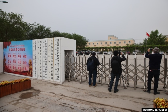 Foreign journalists take photos and record videos outside a location in China's Xinjiang region that was identified in early 2020 as a "reeducation" facility.