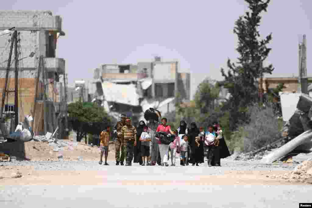 Syrian rebel fighters walk with people who fled their homes due to clashes in Aleppo. (Reuters/Rodi Said)
