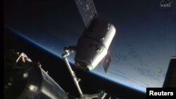 The SpaceX Dragon craft is seen during its maiden voyage to the International Space Station (attached) as it was prepared for its return to Earth in June 2012.