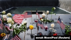 Američke zastave i cveće na ploči s uklesanim imenima u Memoraijalnom centru 11. septembar u Njujorku.