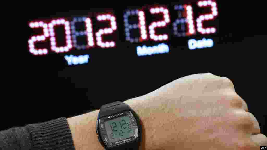 A watch on a person's wrist reading the time "12:12" and the date "12-12-12" for December 12, 2012, in front of a digital clock reading "December 12, 2012" in Paris. It's the 21st century's last sequential date. (AFP/Thomas Coex)