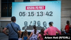 Njerëzit kalojnë pranë ekranit me numërimin mbrapsht në Prishtinë, i cili tregon kohën e mbetur deri në shpalljen e vendimit të Dhomave të Specializuara të Kosovës në rastin ndaj ish-udhëheqësve të UÇK-së. Fotografia është bërë më 11 shtator.