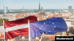 Флаги Латвии и ЕС на фоне города Рига. Иллюстративное фото.