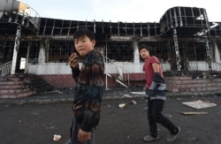 Молодь на тлі спаленої будівлі в селі Масанчі, 8 лютого 2020 року