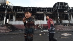 Молодые люди на фоне сгоревшего здания в селе Масанчи. 8 февраля 2020 года.