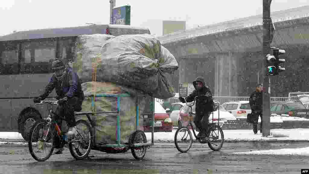 People ride bicycles during a snowfall in downtown Skopje, Macedonia.