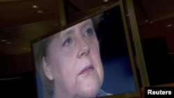 German Chancellor Angela Merkel is seen on a TV monitor as she prepares to record her annual New Year's speech at the Chancellery in Berlin.