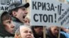 Ukrainian protesters hold up a sign reading "Stop the crisis!" in Kyiv. Berglof says there will be "several months of difficult time for Ukrainian companies and Ukrainian households."