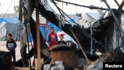  Палестински деца преглеждат мястото на израелски удар по палатков лагер за разселени хора в региона Ал-Маваси в Хан Юнис в южната част на Ивицата Газа, 18 март 