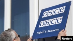 Belarus -- An OSCE employee removes signage from the OSCE office in Minsk, 29Mar2011