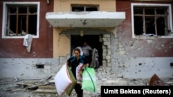 Residents carry their belongings from their damaged homes after a cease-fire began during the fighting over the breakaway region of Nagorno-Karabakh in the city of Terter, Azerbaijan.