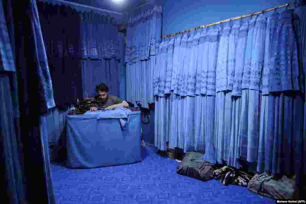 An Afghan tailor stitches burqas inside a shop in the western city of Herat on May 13. Conditions for women and girls have drastically declined since the Taliban's 2021 takeover of Afghanistan with women now required to cover their faces in public.Photo by Mohsen Karimi/AFP.