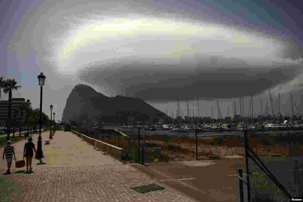 People walk along a street in front of the Rock of the British territory of Gibraltar (rear), a monolithic limestone promontory, next to the border in La Linea de la Concepcion, southern Spain. (Reuters/Jon Nazca)