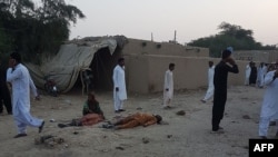 Pakistani devotees gather around the bodies of blast victims after a suicide bombing near a Sufi shrine in the Jhal Magsi district on October 5.