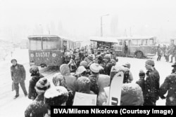 Navetiști, dintre care câțiva cu schiuri, așteaptă să urce în autobuze spre muntele Vitoșa în 1974. Masivul Vitoșa se profilează deasupra Sofiei și este unul dintre simbolurile capitalei bulgare.