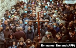 Христианские верующие несут деревянный крест вдоль Виа Долороза (Путь страданий) в Старом городе Иерусалима во время шествия Страстной пятницы, 2 апреля 2021 г.