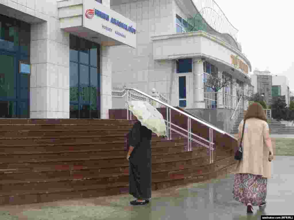 Ýagynly howada adamlar dermanhananyň açylmagyna garaşýarlar.