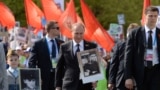 RUSSIA – Russian President Vladimir Putin (C) carries a portrait of his father as he takes part in the Immortal Regiment march during the Victory Day celebrations in Moscow on May 9, 2015