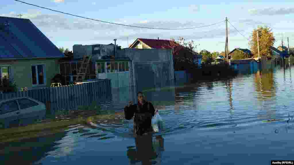 A man makes his way through a flooded street.