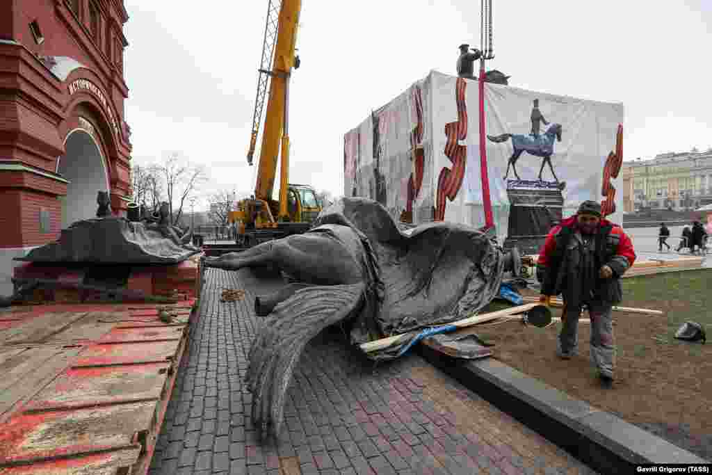 A worker with a power tool at the site. Photographs taken by a TASS photographer appear to show the original statue has been cut into pieces. 
