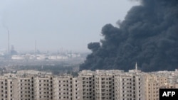 A thick plume of smoke rises above an oil refinery, situated to the west of the flashpoint city of Homs on December 8. 