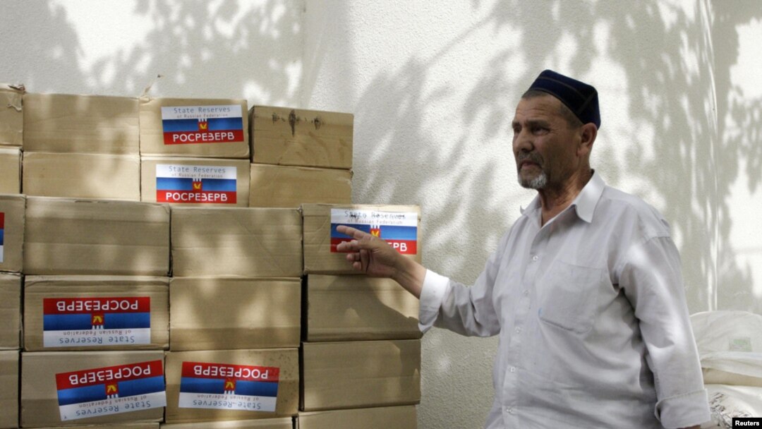 A refugee stands by boxes with humanitarian aid in the town of Osh 