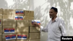 A refugee stands by boxes with humanitarian aid in the town of Osh 