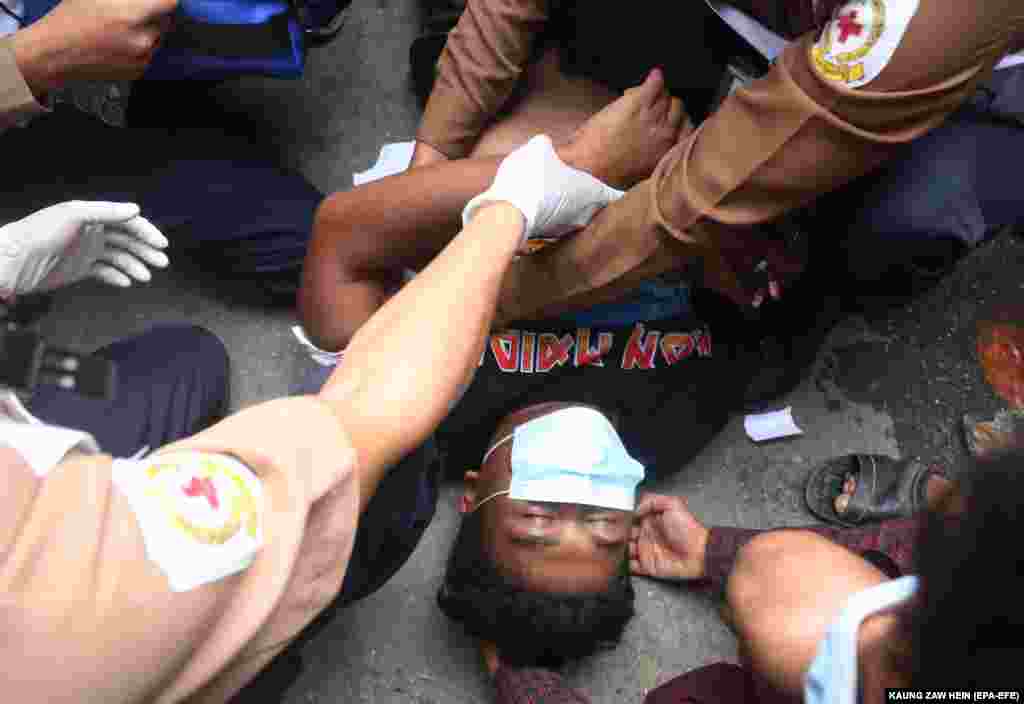 An injured man is being cared for by medical staff after police fired at protesters during a protest against the military coup in Mandalay, Myanmar, 20 February 2021.
