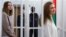 Katsyaryna Andreyeva (right) and Darya Chultsova stand inside the defendants' cage during the court hearing in Minsk on February 18.
