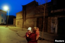 Женщина несет ребенка на руках в Кашгаре. Синьцзян, Китай, 23 марта 2017 года.