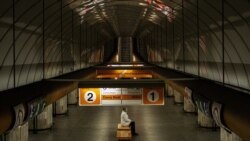 Žena sa zaštitnom maskom na klupi prazne stanice metroa u Pragu, 15 april 2020.