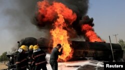 Afghan firefighters attempt to extinguish a burning fuel tanker which was hit by a magnetic bomb on the outskirts of Jalalabad