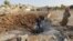 Men stand around a crater caused by what activists say was a Russian air strike in Latamineh on September 30 in the northern countryside of Hama.