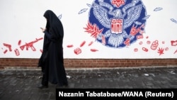 A woman walks past an anti-American mural on the former US Embassy's wall in Tehran (file photo)