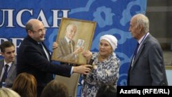 Конференция ачылышында Аяз Гыйләҗевнең хатыны Нәкыя Гыйләҗева (уртада) Арпад Галгоцига (уңда) бүләк тапшыра.