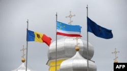 Moldova -- Flags of Moldova (L) and Gagauzia (C) wave next to a Russian Orthodox church in Comrat city, the main city of Gagauzia, April 6, 2014