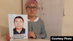 Бикамал Какенкызы держит портрет мужа Адильгазы, заключенного в китайскую тюрьму