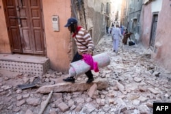 Një burrë duke ecur me gjësendet e tij nëpër gërmadha në një rrugicë në qytetin e vjetër, Marakesh, pas tërmetit shkatërrues më 9 shtator 2023.