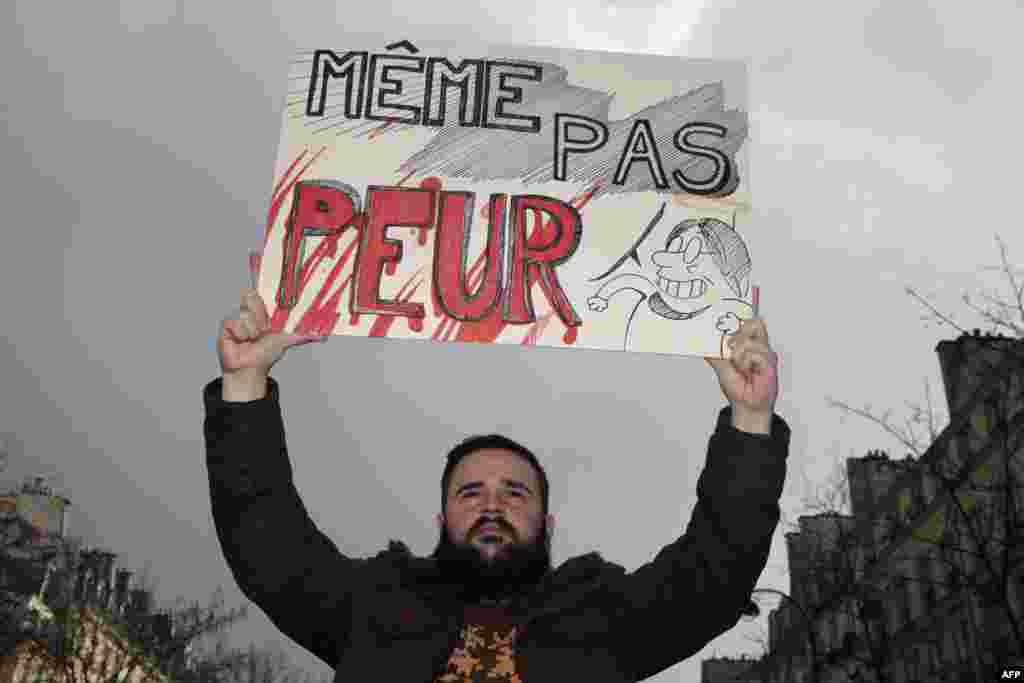 A man holds a sign that reads &quot;Not even scared&quot; at the start of the rally in Paris.