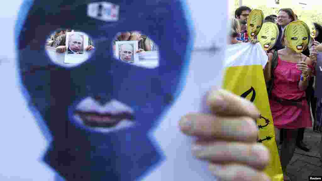 Activists wear masks in support of Pussy Riot and hold banners depicting Russian President Vladimir Putin during a protest in front of the Russian delegation to the European Union in Brussels on August 17.