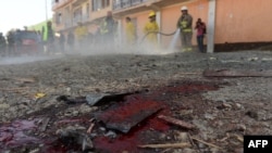 Afghan firefighters wash blood off a road at the site of a suicide attack in Kabul on October 2, 2014