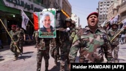 FILE - Members of Iraq's Shiite Muslim Hashed al-Shaabi (Popular Mobilisation units) paramilitary force carry the coffin of a comrade during his funeral procession on August 26, 2019