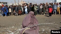 FILE: An internally displaced Afghan woman waits to receive assistance donated by a nongovernmental organization in Kabul.