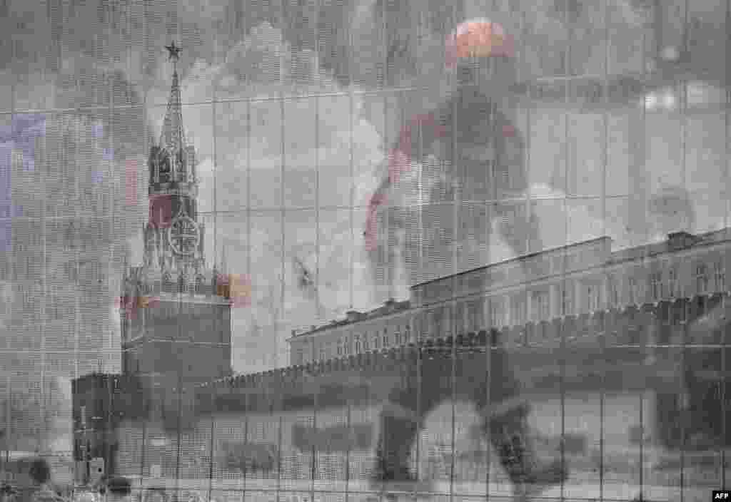 A worker passes behind a transparent fence bearing an image of Red Square at a construction site outside the Kremlin in Moscow. (AFP/Aleksandr Nemenov)