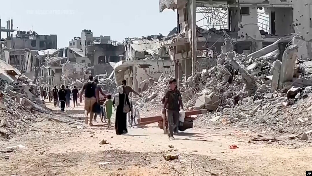 Unii refugiați palestinieni se întorc în cartierul Shujaiya din Gaza City, devastat de lupte.