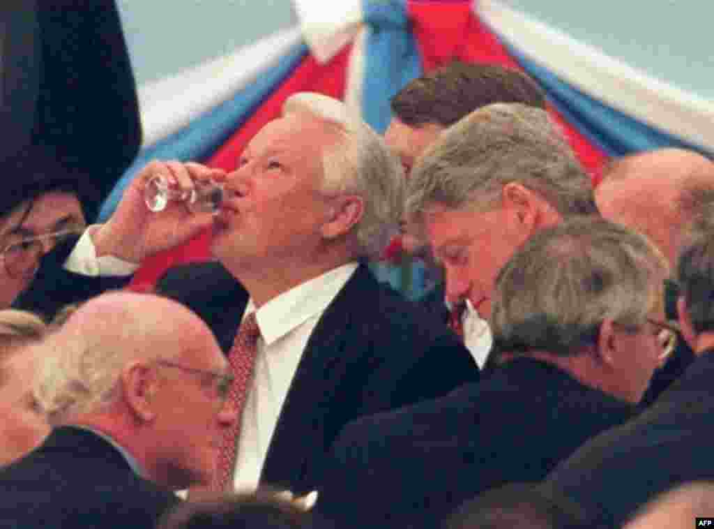 Yeltsin drinks a toast with Western leaders ahead of a ceremony commemorating the 50th anniversary of the end of World War II in Europe on May 9, 1995 (AFP) - Russia – Geopolitics / Personalities – President Boris Yeltsin (C) finishing a glass of vodka at a reception of heads of state in the Kremlin, with British Prime Minister John Major (foreground) and U.S. President Bill Clinton (R of Yeltsin), Moscow, 09May1995. Source: AFP.